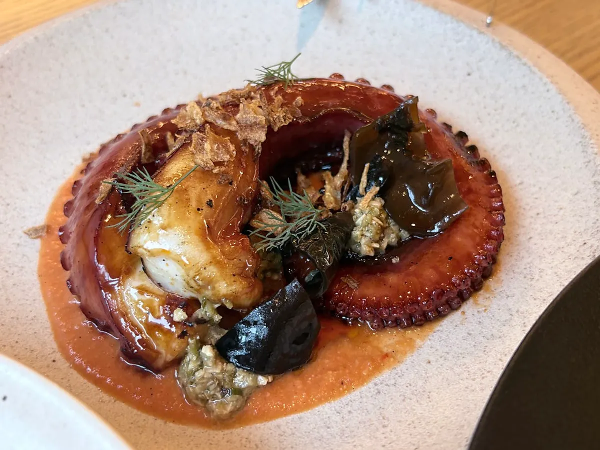 Charcoal-grilled octopus leg placed on romesco sauce