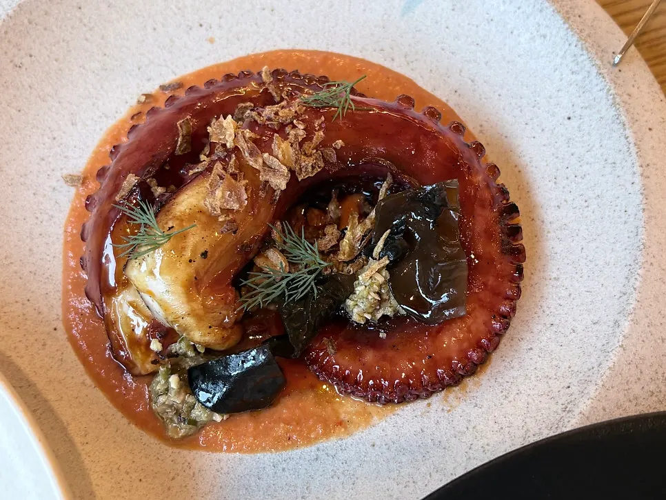 A cut piece of charcoal octopus dipped in sauce