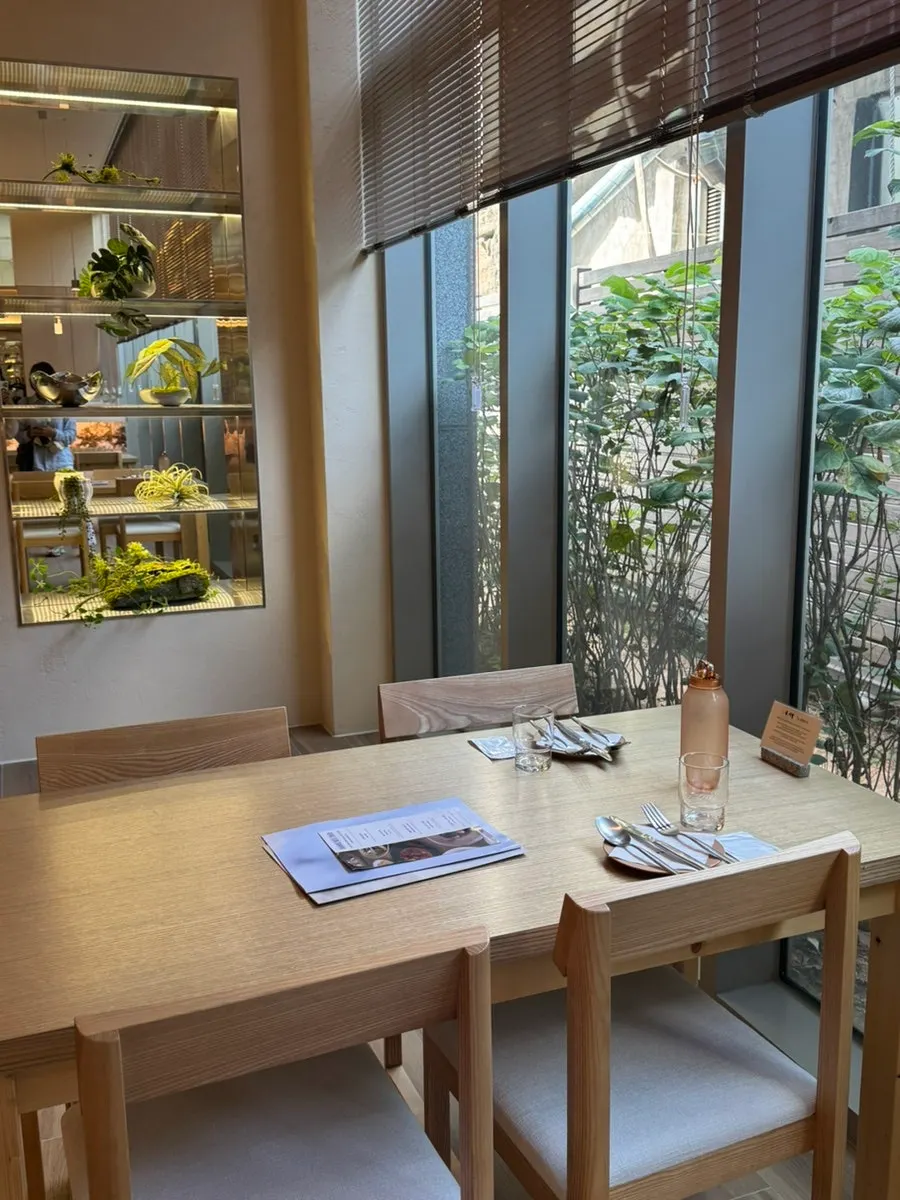 Window seat with a view of green plants through floor-to-ceiling windows