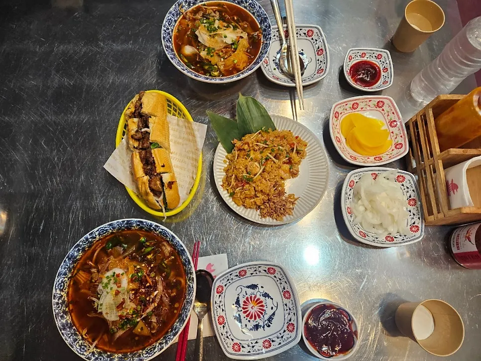 A full table with pho, pad thai fried rice, and bánh mì