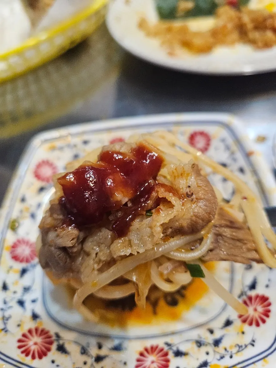 A spoonful of spicy pho broth lifted from the bowl