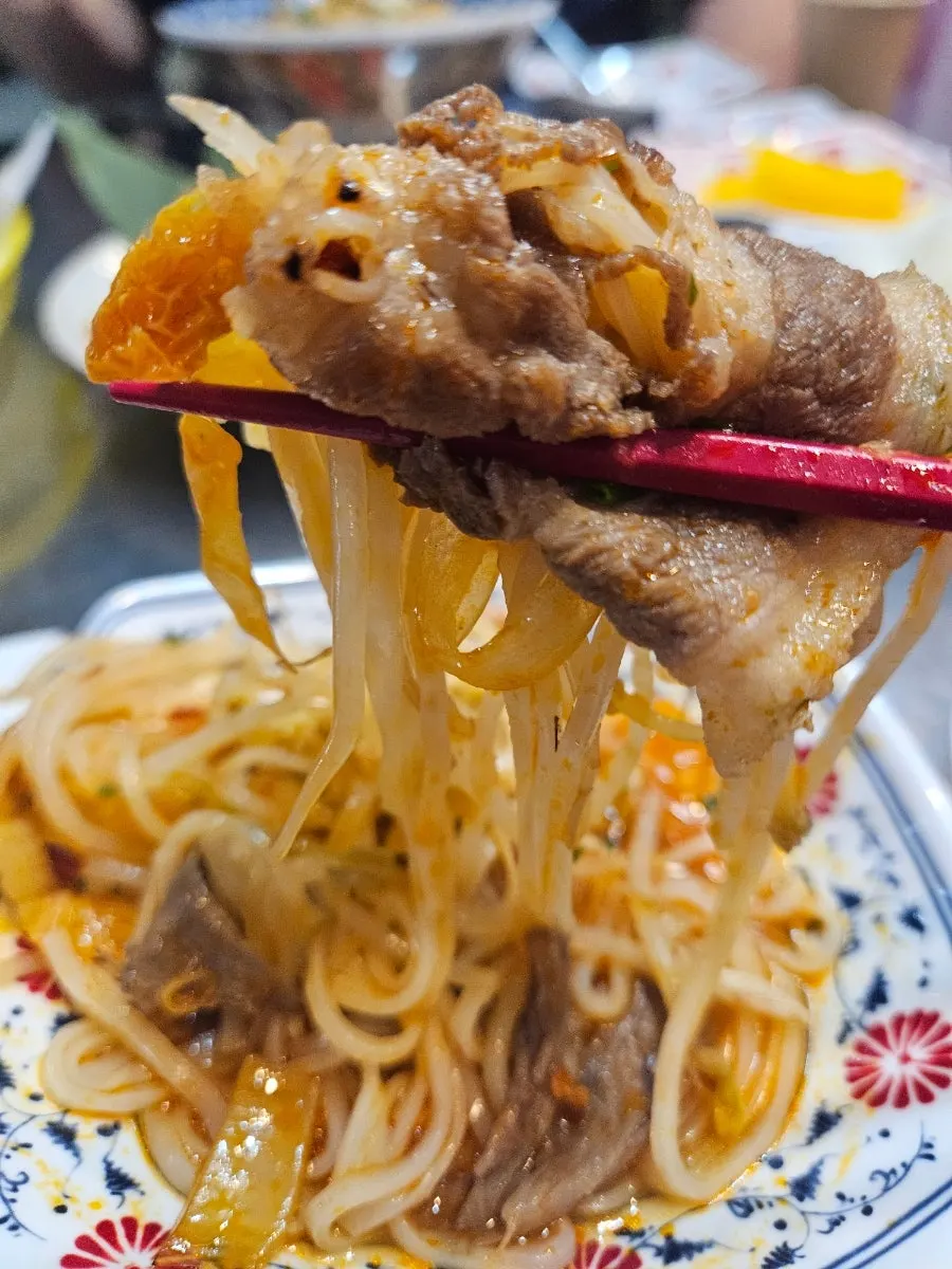Pho noodles and meat lifted up with chopsticks