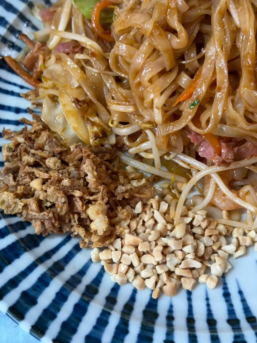 Pad thai mixed with crushed peanuts and onion flakes