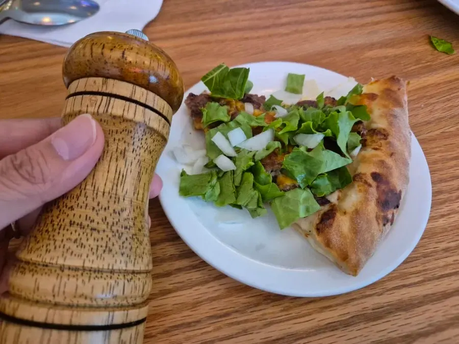Salt set out on the table alongside a pizza crust