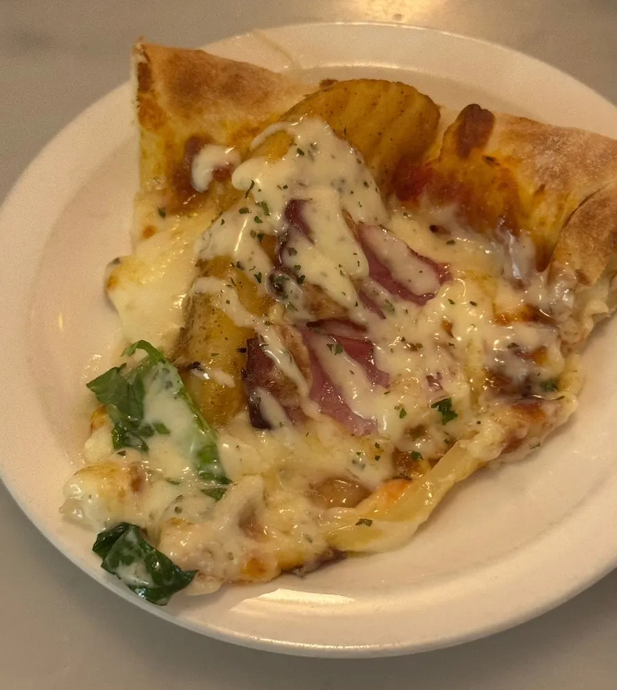 Beef cheeseburger pizza piled with raw onion and green vegetables