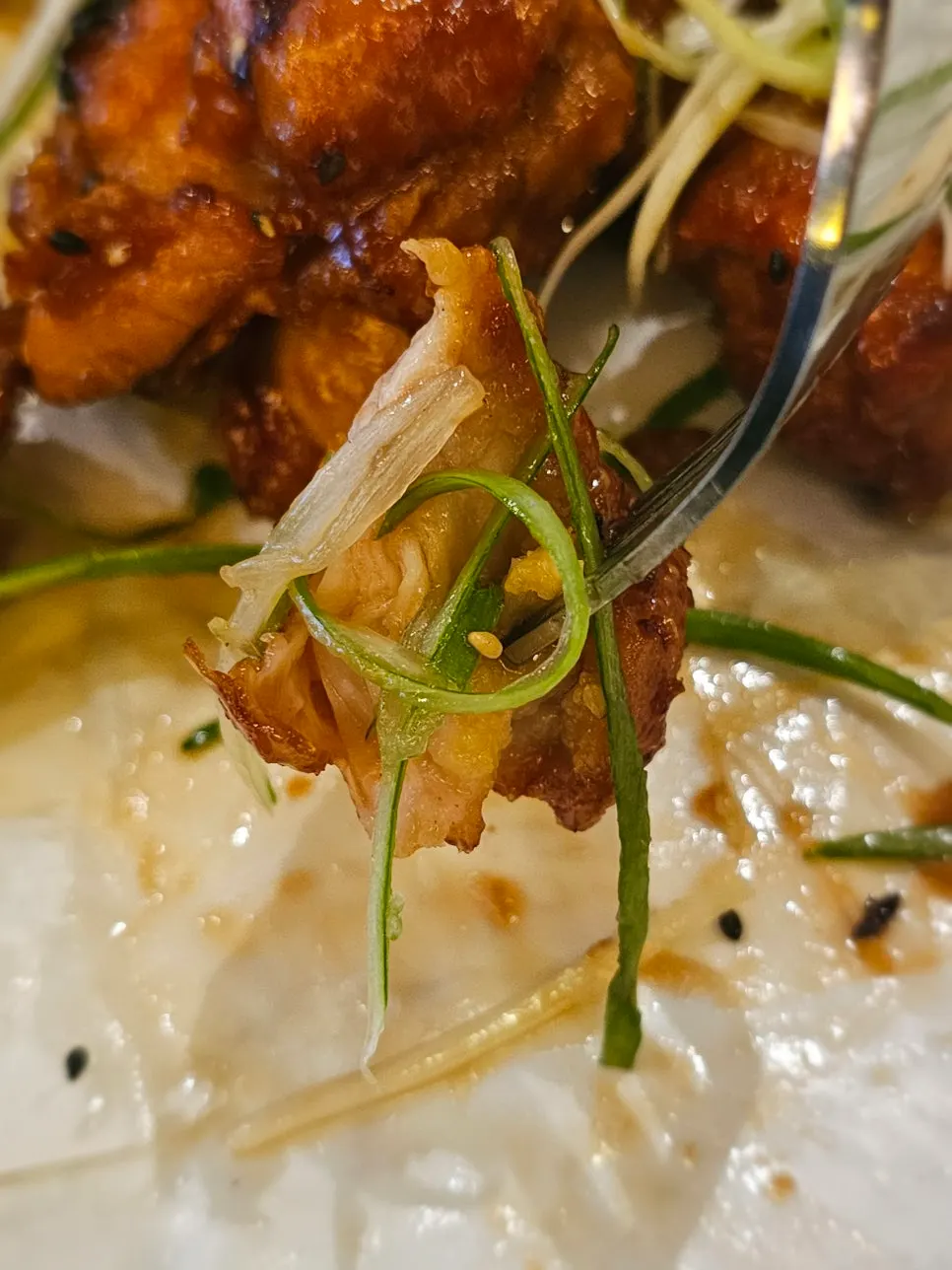 A piece of chicken piled high with scallion shreds