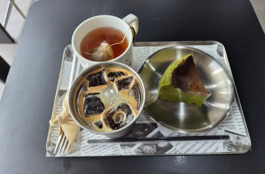 Table with matcha basque cheesecake, coffee, and tea