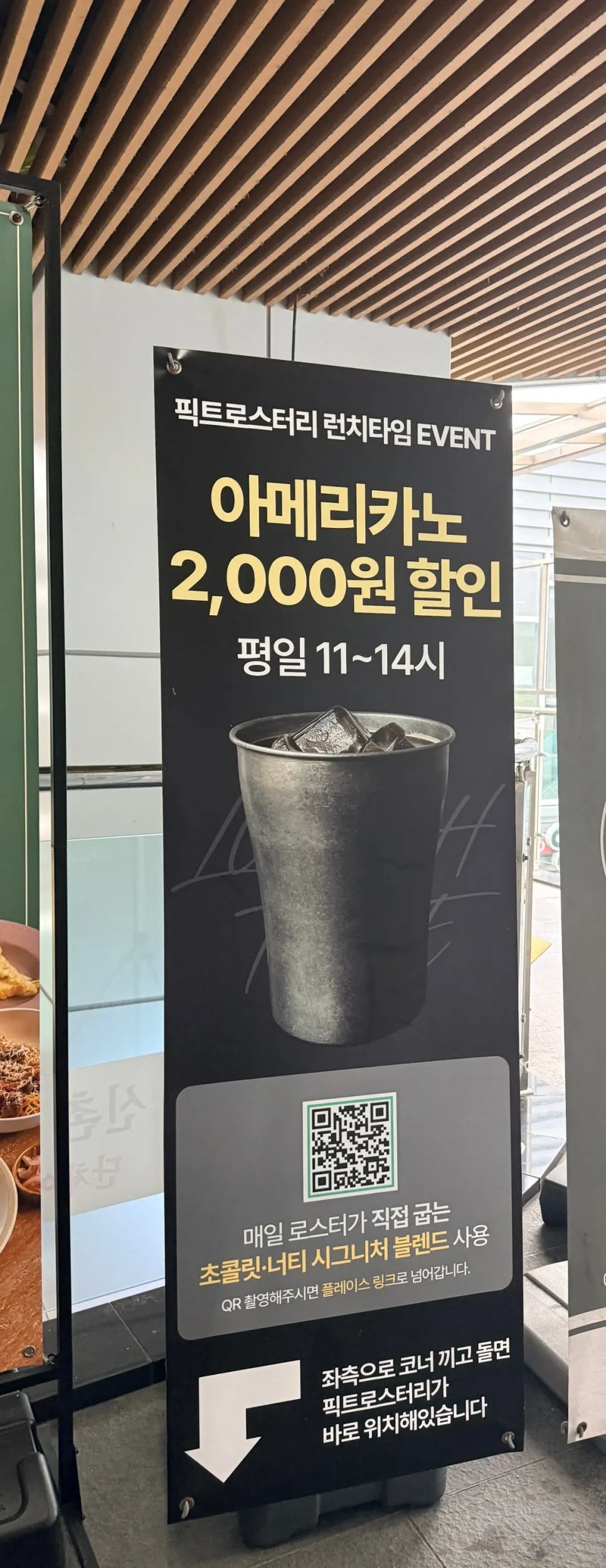 엘리베이터 앞 픽트로스터리 입간판과 평일 아메리카노 할인 안내