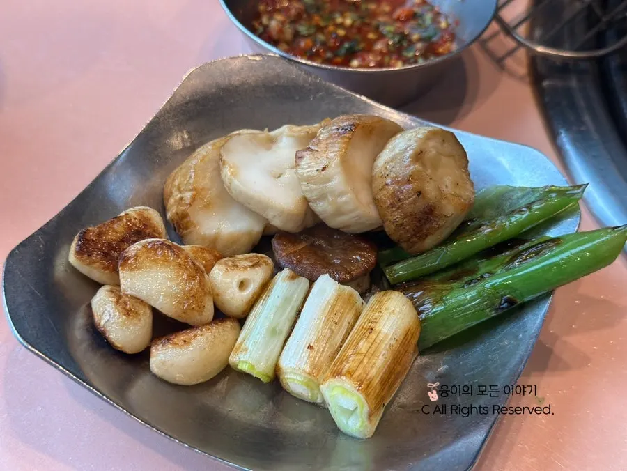 Grill neatly arranged with garlic, king oyster mushroom, and grilled green onion