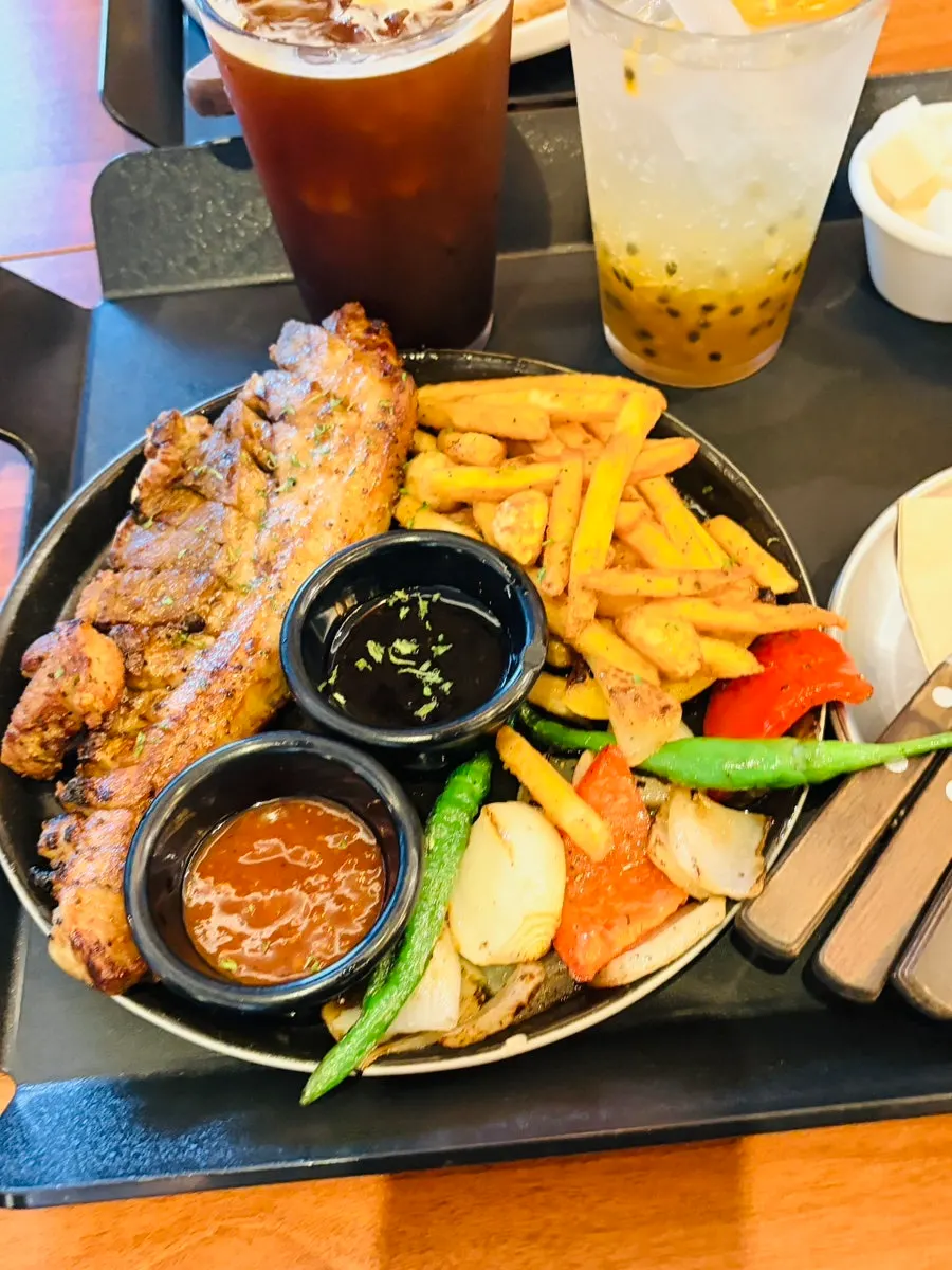 Pork belly steak plate with side vegetables and sauces