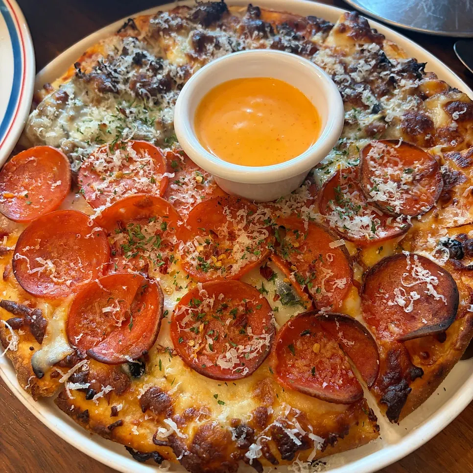 A slice of half-and-half pizza dipped in chipotle sauce