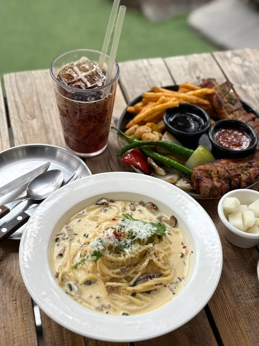 Table setting with charcoal-grilled pork belly steak platter and truffle cream pasta at Pino Cafe