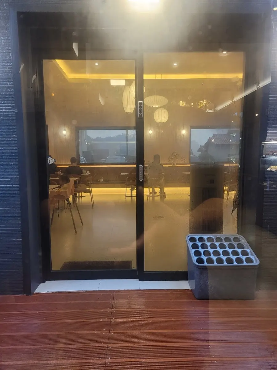 Pino Cafe's annex with yellow light glowing through floor-to-ceiling glass doors