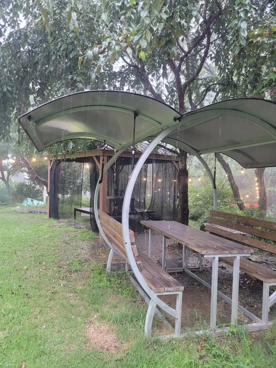 Wooden outdoor bench and table built together under a wide roof