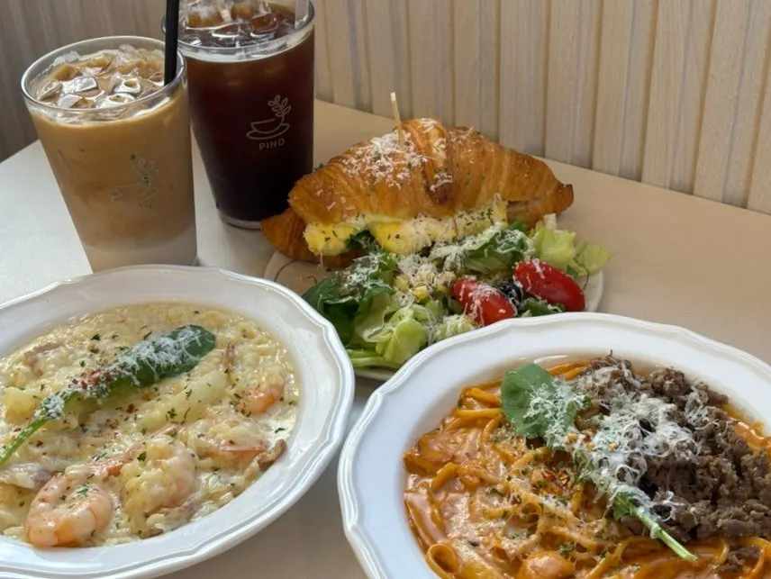 Table full of pasta, risotto, sandwich, and coffee
