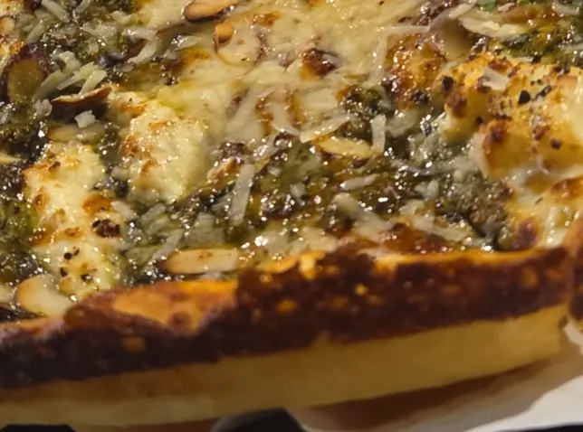 A slice of basil pesto gorgonzola pizza