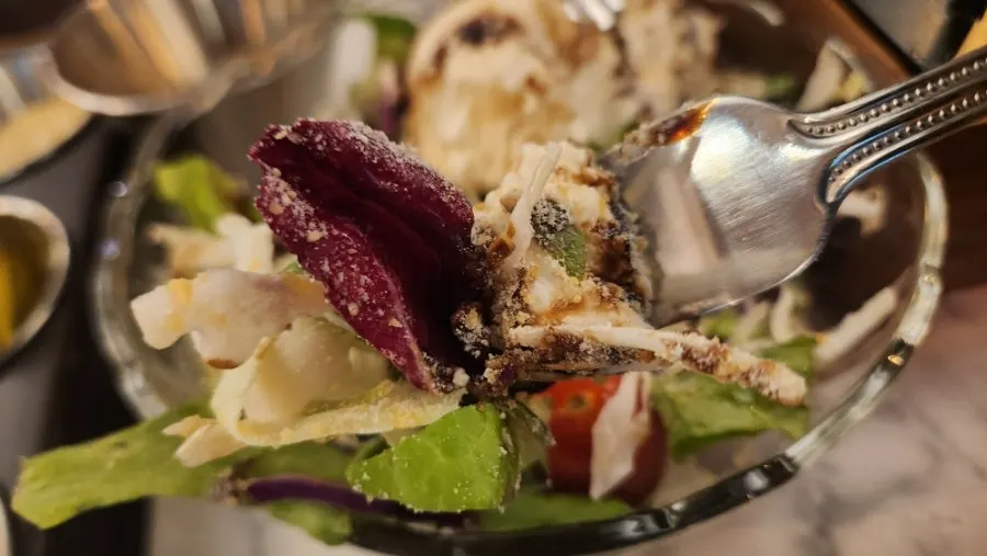 Salad topped with a large scoop of ricotta cheese