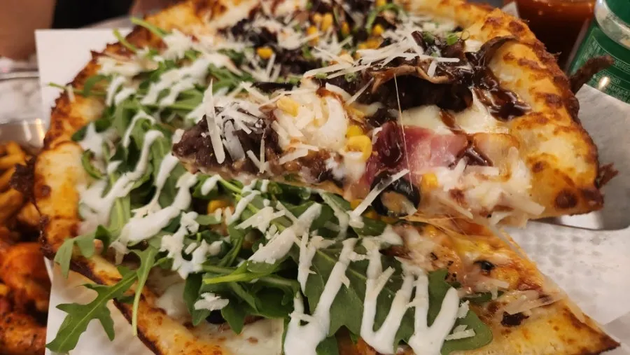 Slice of Philly cheese barbecue steak pizza loaded with toppings