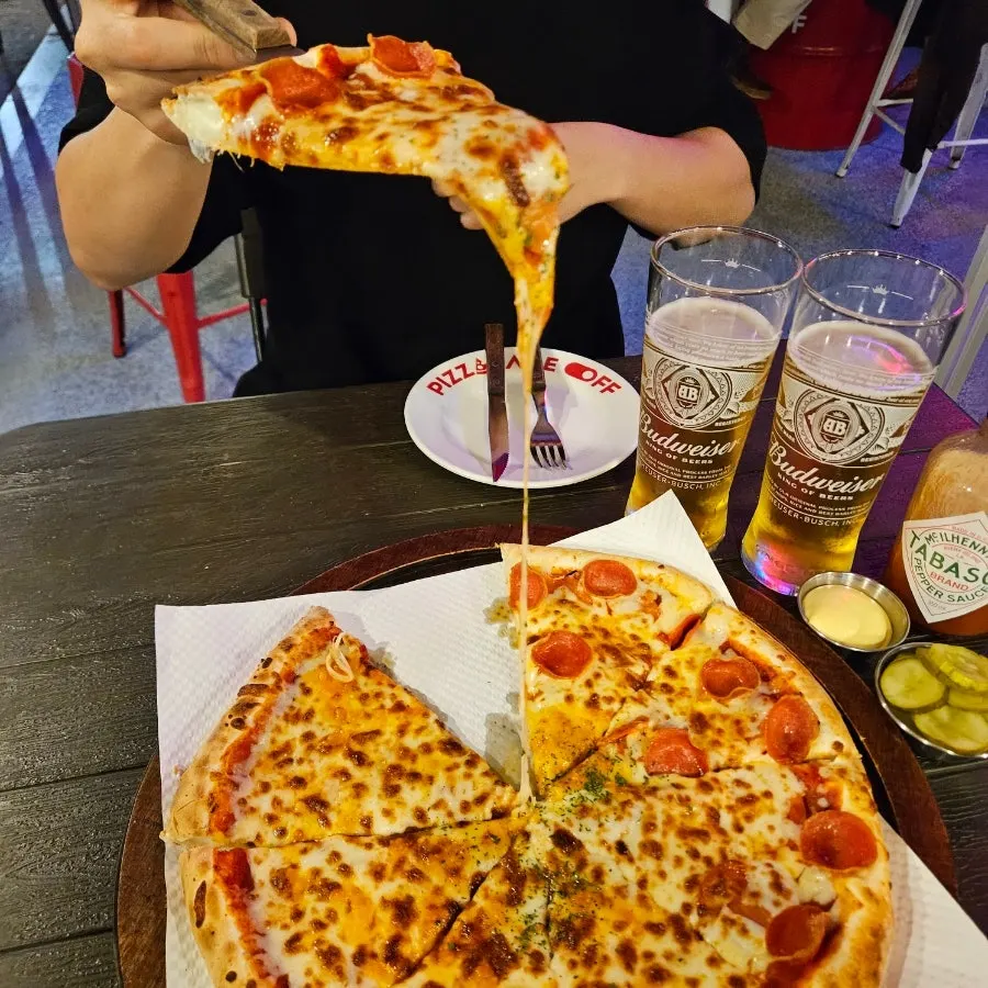 Pizza served with hot sauce and beer