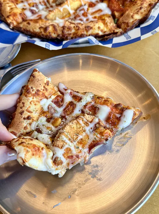 A slice of potato pizza dipped in sauce