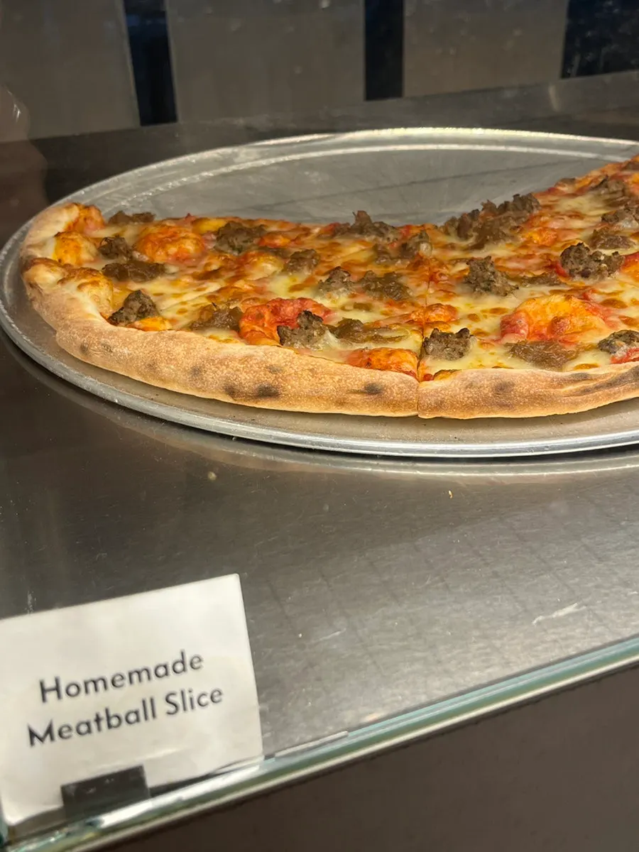 Display case of pizza slices loaded with toppings
