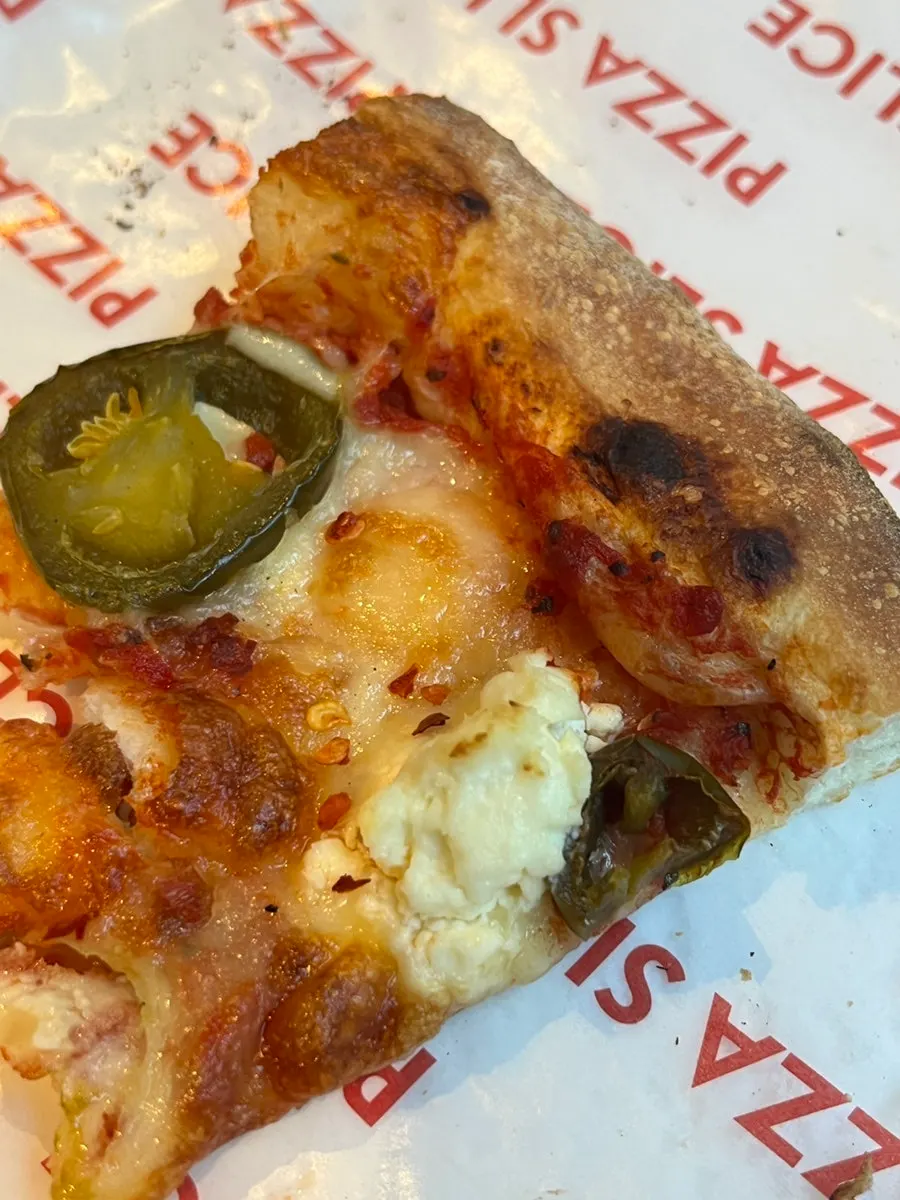 Pizza slice enjoyed with sauces on the side