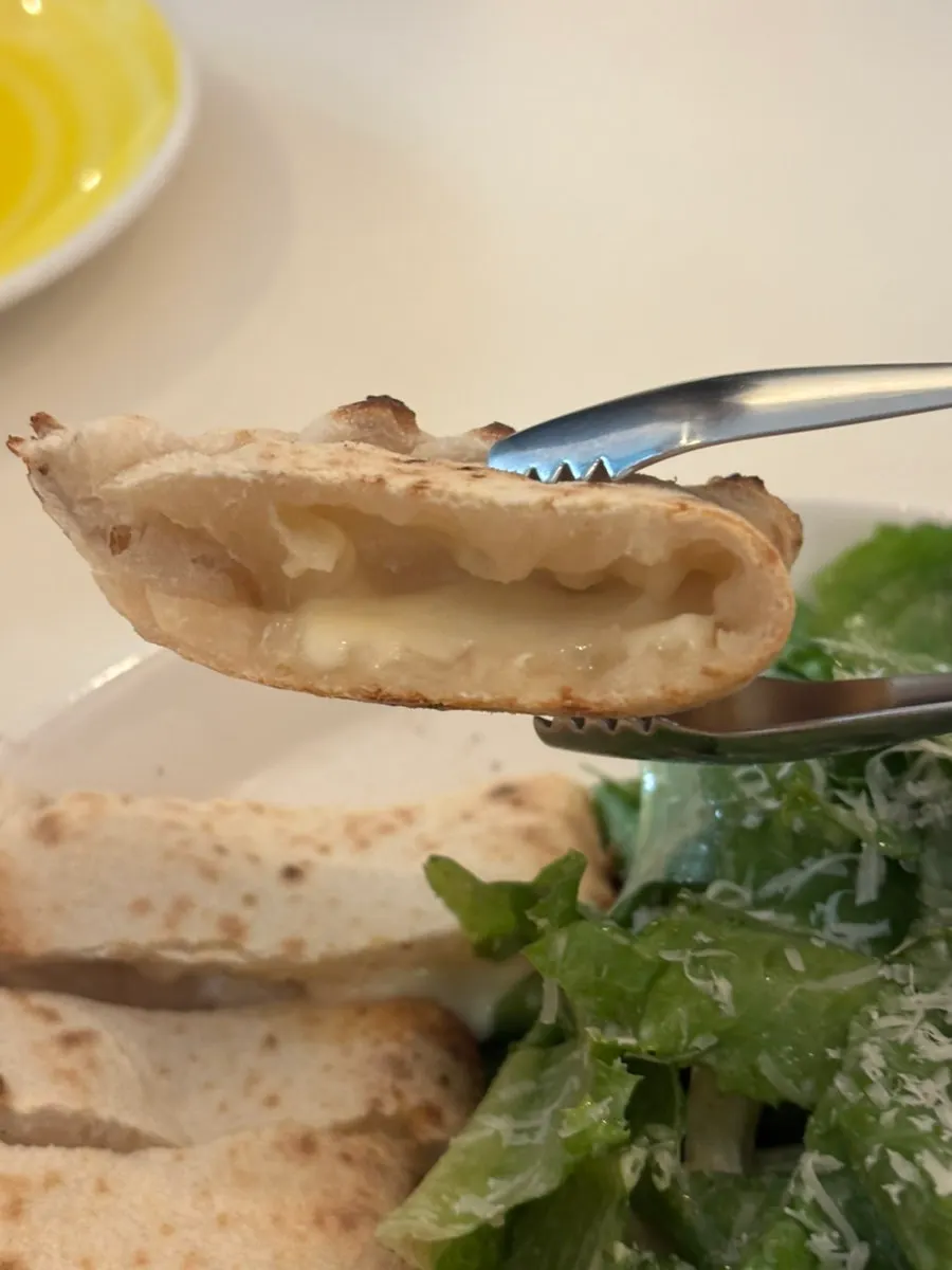 Half-moon-shaped cheese bread on top of the Caesar salad