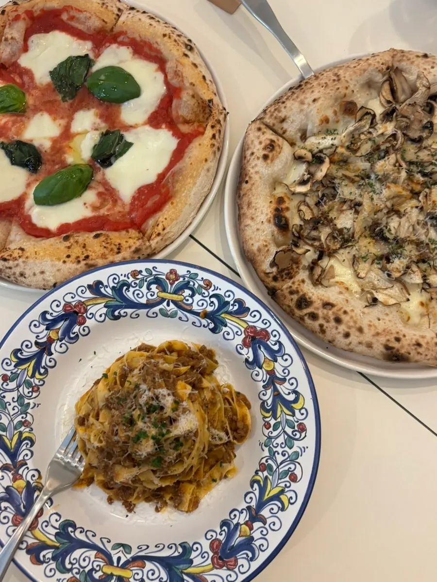 Table with two pizzas and ragu pasta