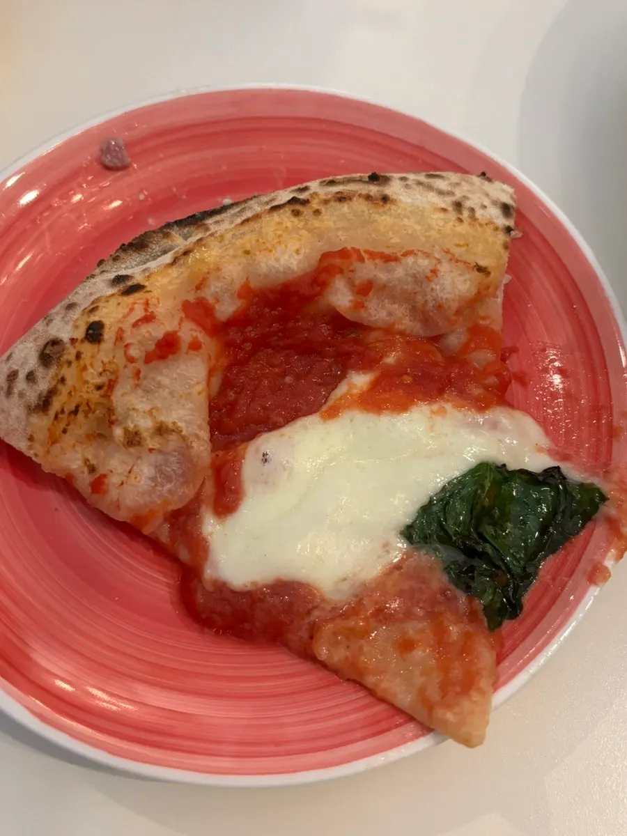 A slice of Margherita Bufala topped with basil leaves
