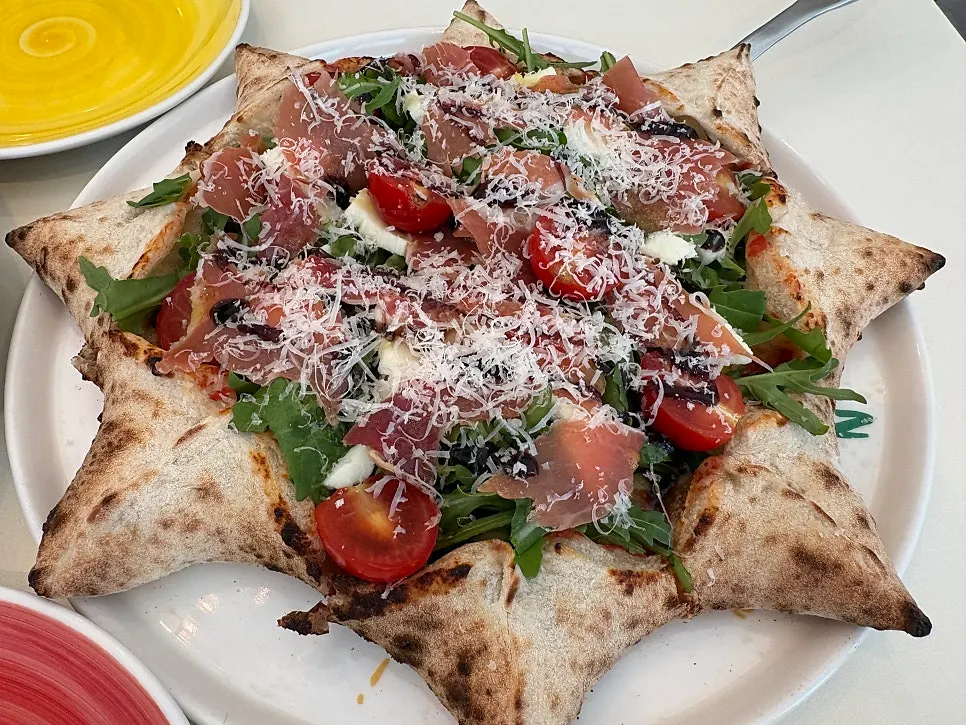 Wood-fired pizza with pointed crust edge and rocket toppings