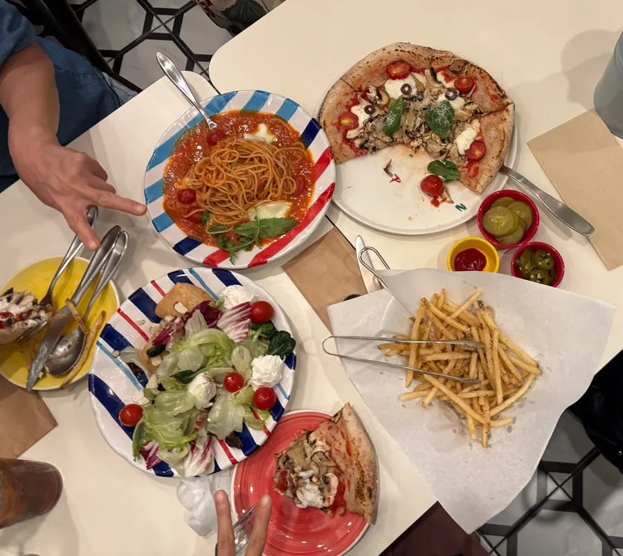 Table with pizza, pasta, and salad laid out