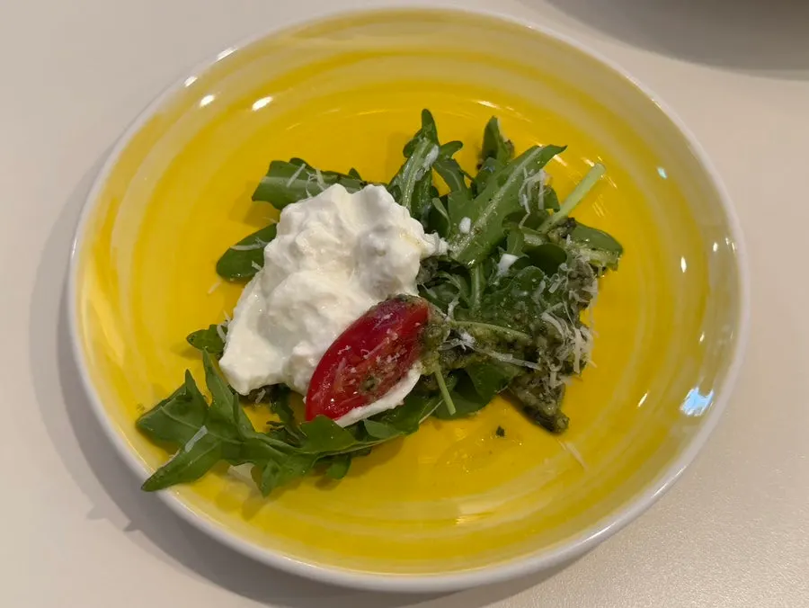 Fresh burrata cheese salad on a yellow plate
