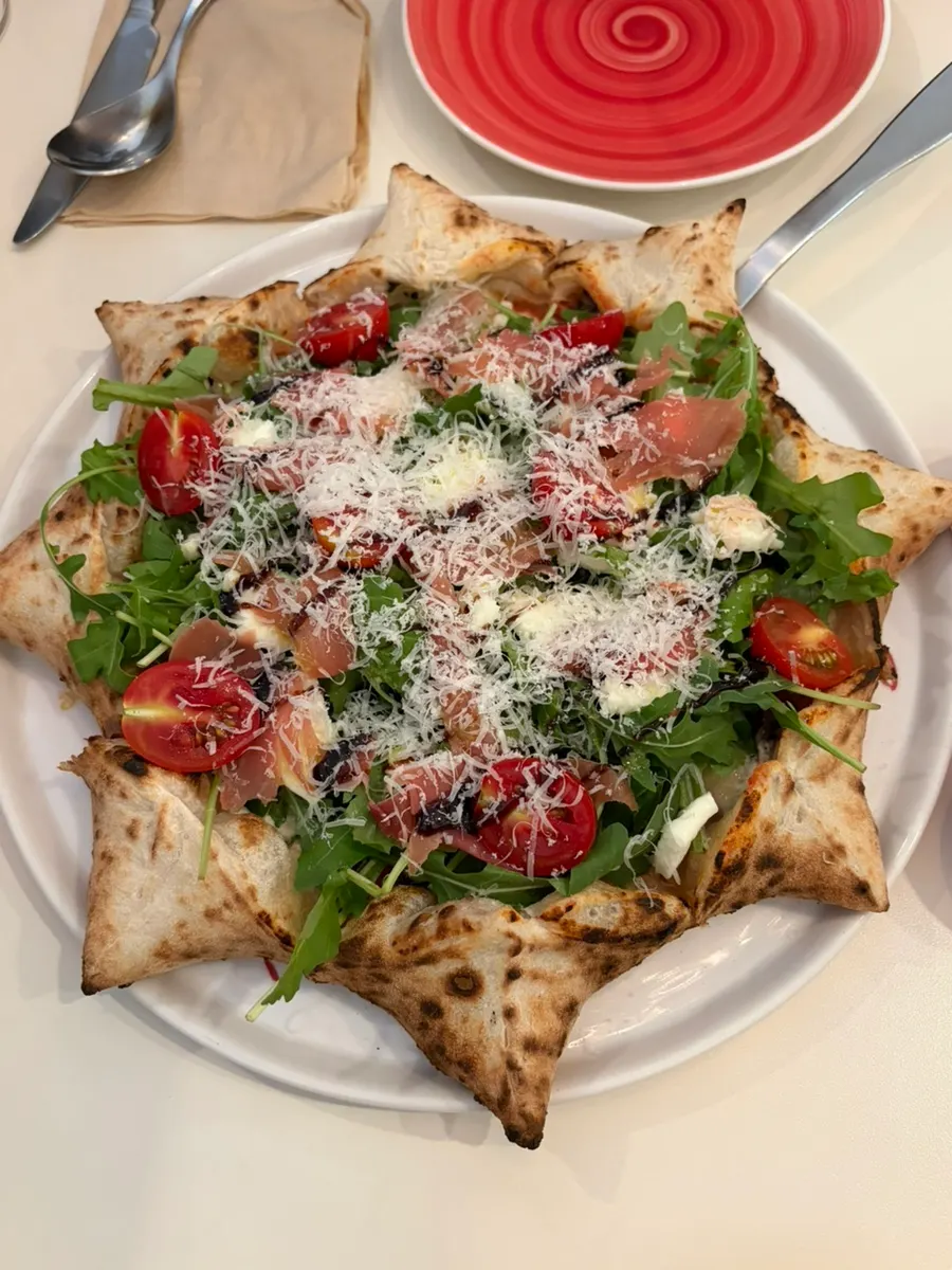 Stella pizza piled with prosciutto and arugula