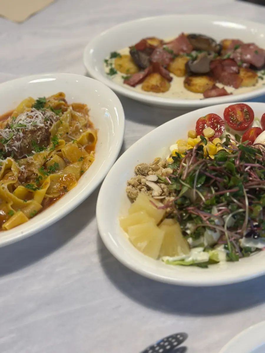 Mesa servida con ñoquis, ensalada y pasta