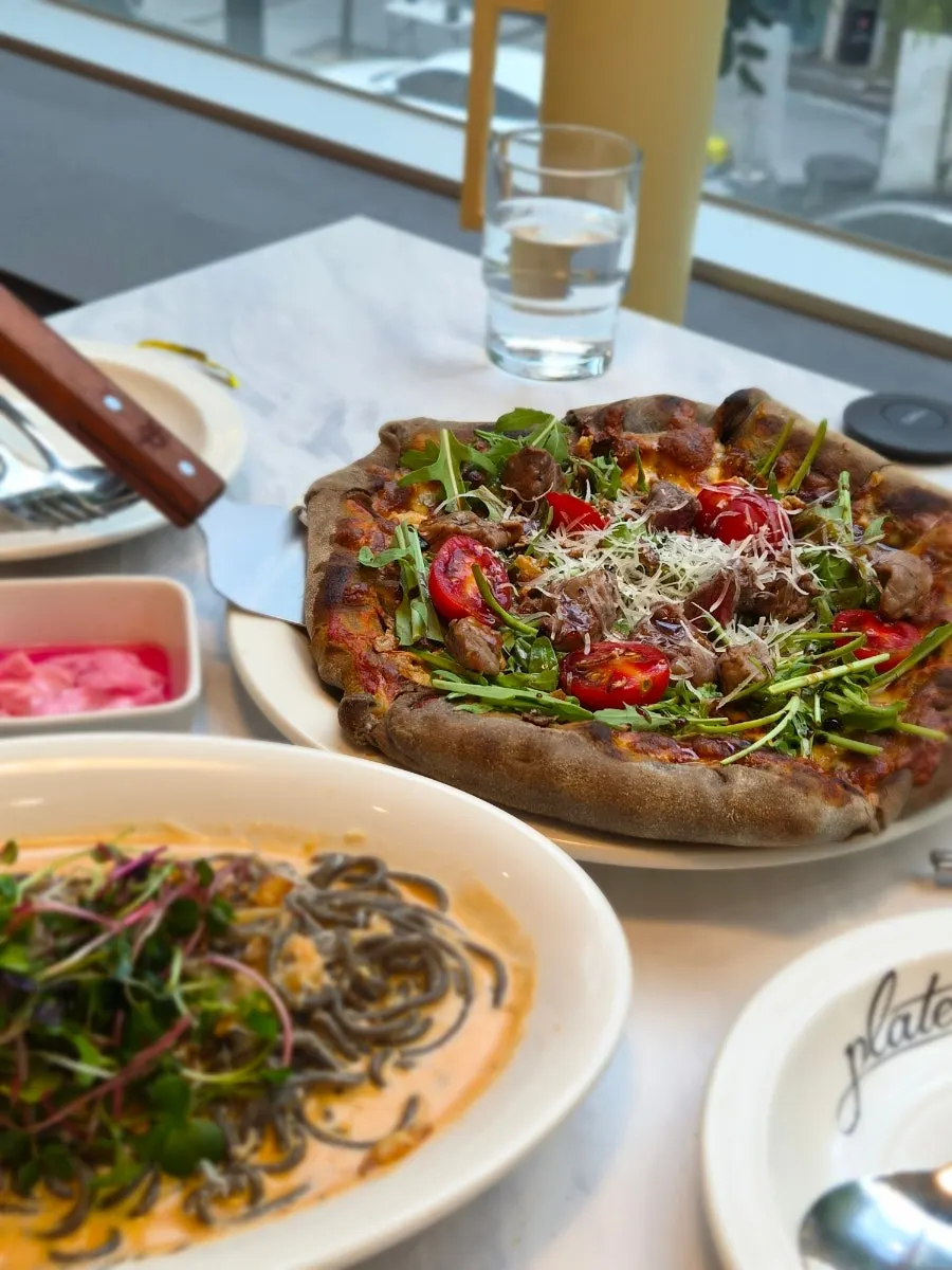 Fire-grilled chapsteak pizza and squid ink creamy rosé pasta on the table
