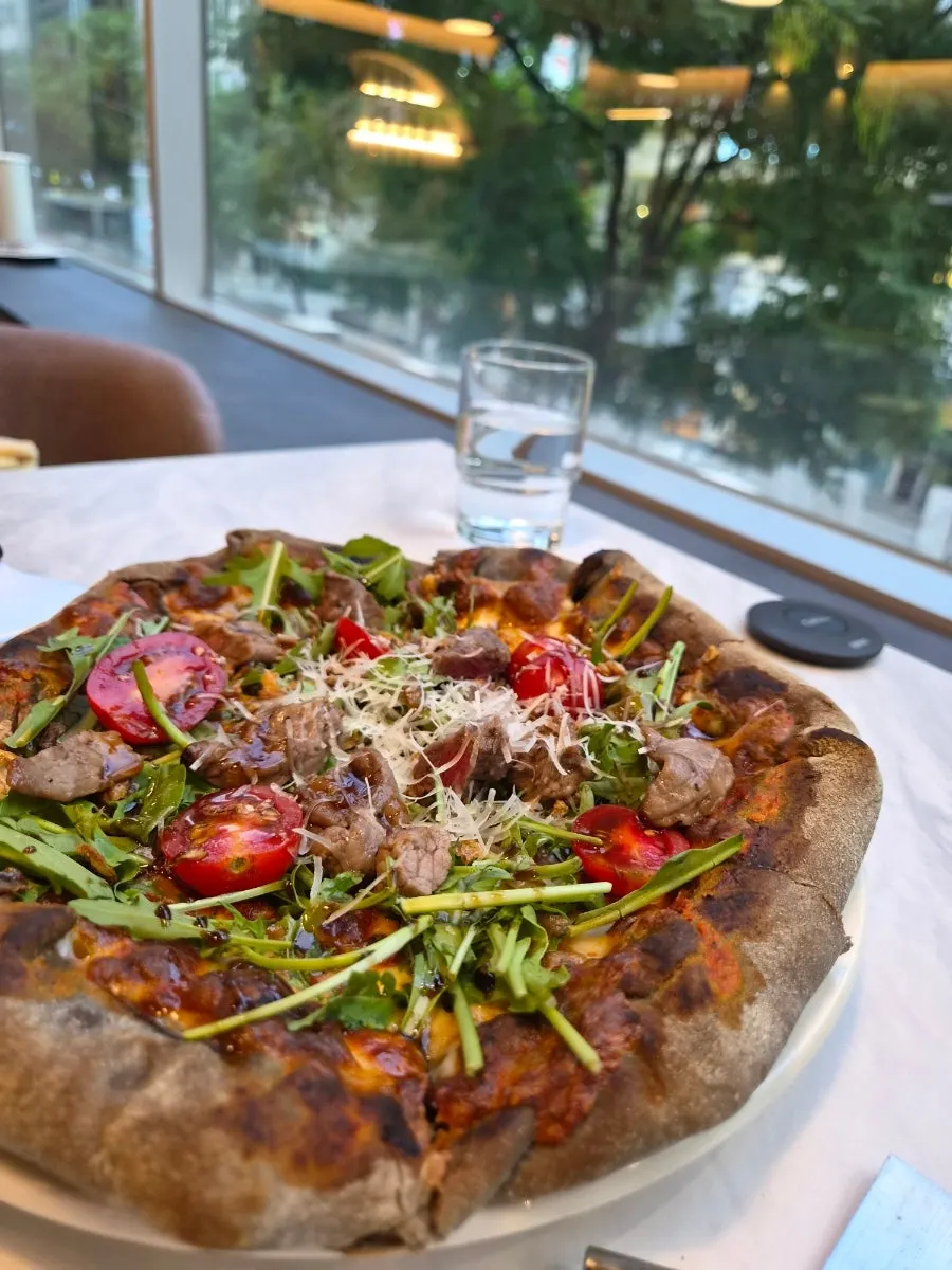 A slice of fire-grilled chapsteak pizza piled with meat topping