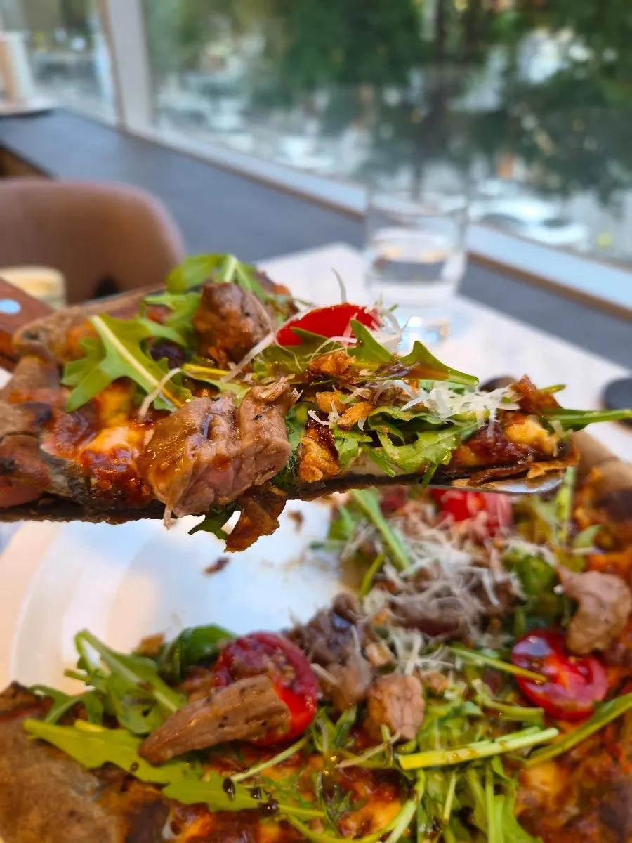 A lifted slice of chapsteak pizza