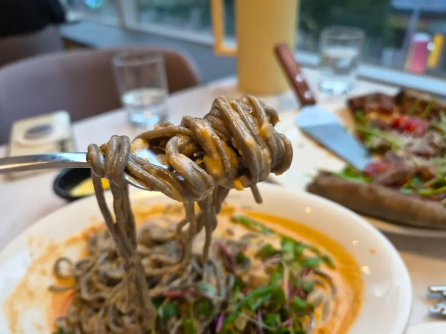 Black squid ink noodles lifted with a fork from the creamy rosé pasta
