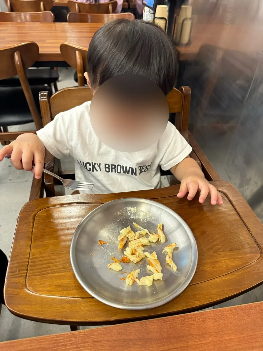 Vertical photo of baby eating pizza at the table