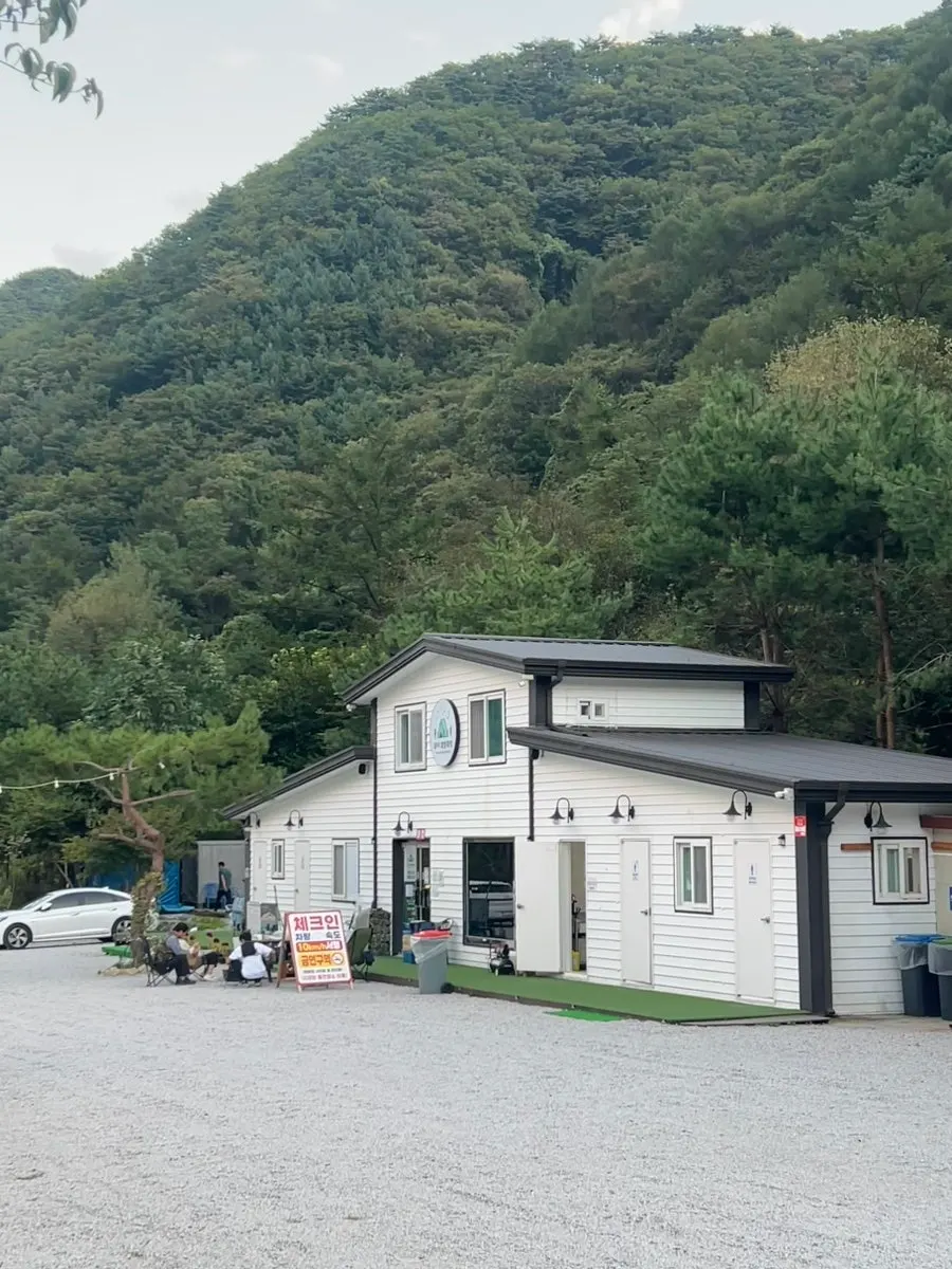 Forest view and parking lot at Byeolbit Camping Site, surrounded by mountains