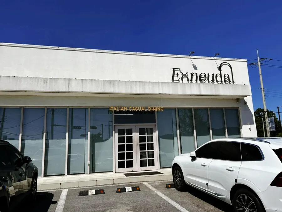 White-toned building with floor-to-ceiling windows and front-yard parking at Eoneu Dal