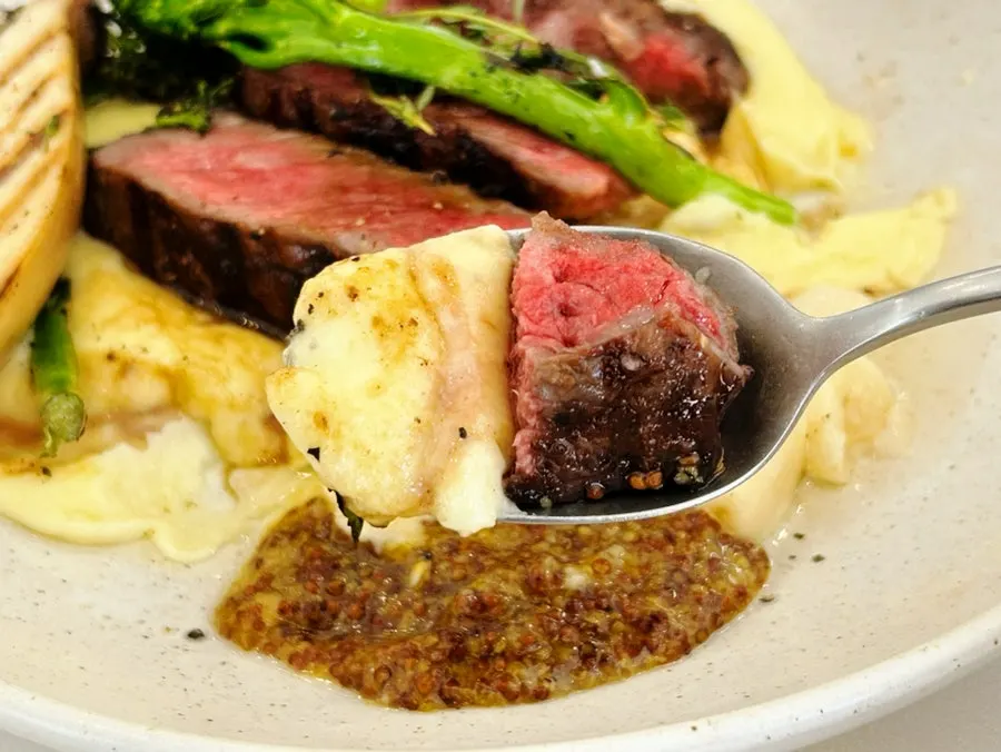 A bite of steak topped with wholegrain mustard