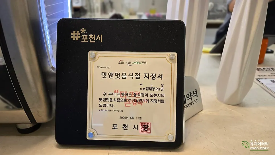 카운터에 놓인 포천시 맛앤멋 음식점 지정서