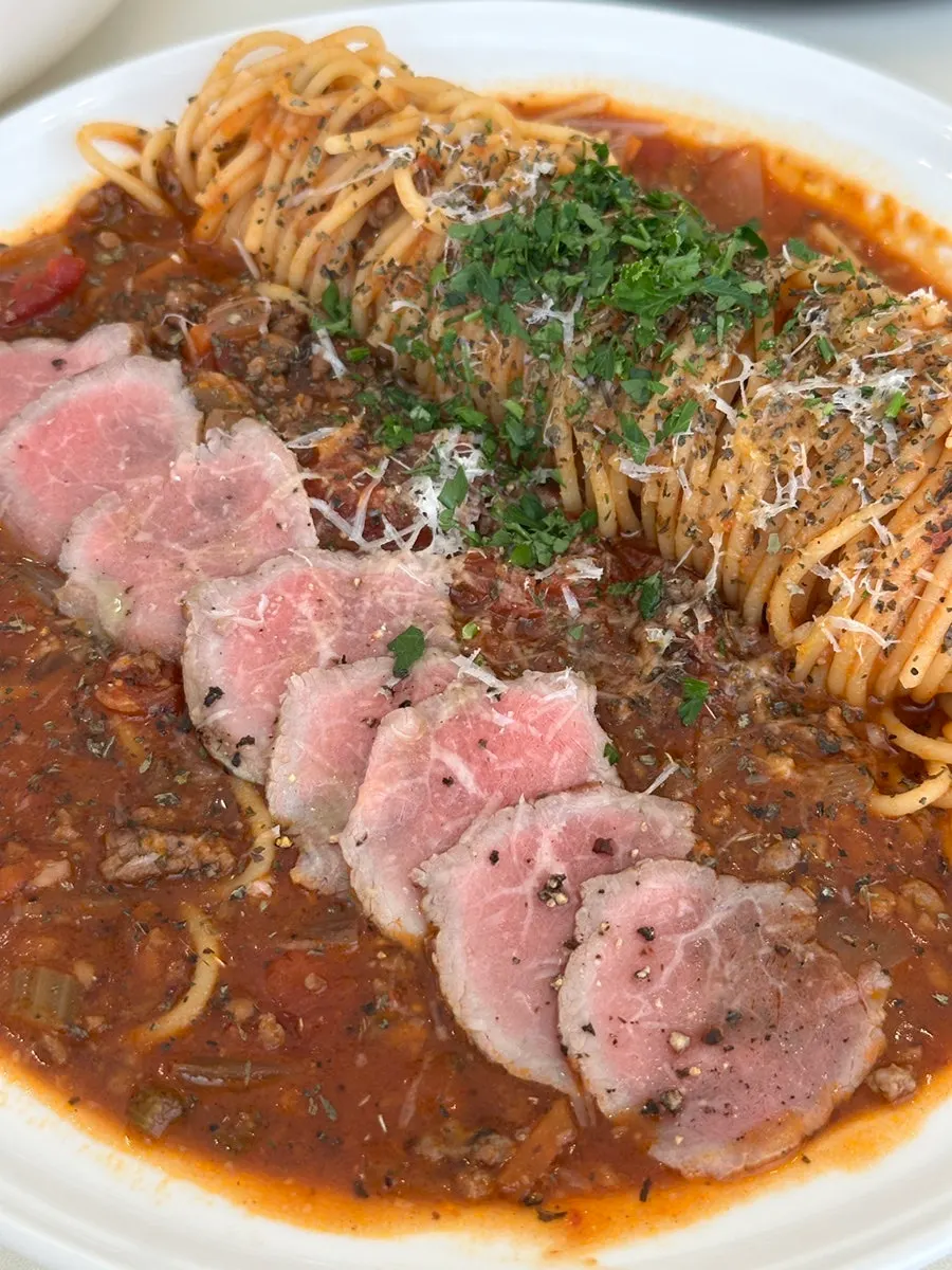 Thinly sliced beef on top of tomato pasta