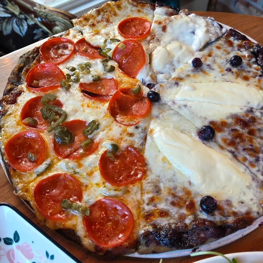 Pizza slice topped with fresh blueberries and cream cheese