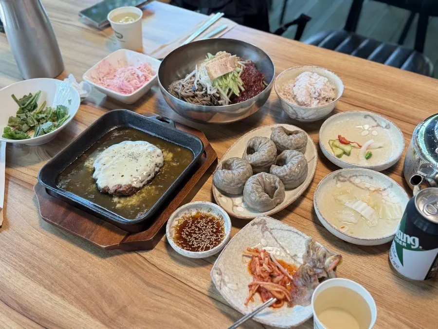 A full table for two with tteokgalbi, makguksu, and mandu