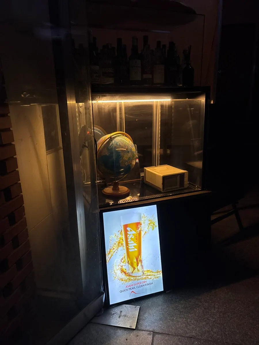 Glass display case at the entrance with a globe and whiskey bottles