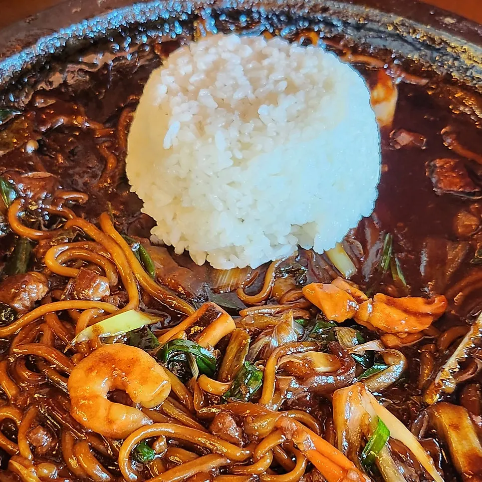 Portion of stone-plate seafood jjajang scooped into a child's bowl