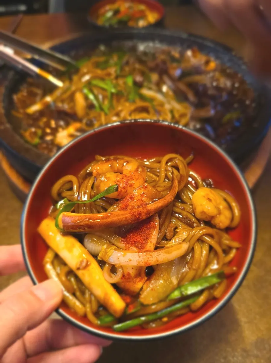 Close-up of stone-plate seafood jjajang with visible shrimp and squid