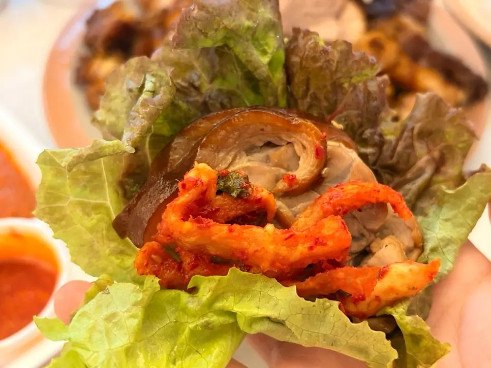 Lettuce wrap topped with jokbal and dried radish kimchi